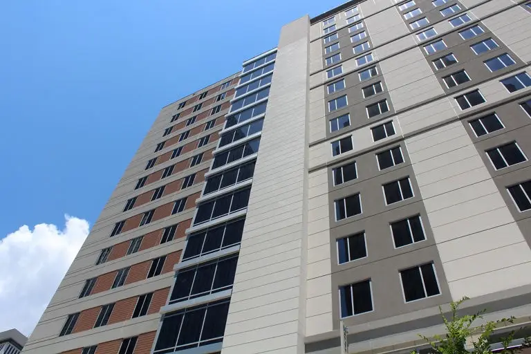 Tall modern apartment buildings with contrasting beige and brown facades featuring regular window patterns against blue sky