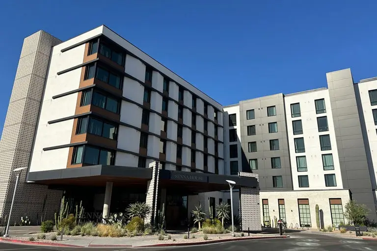 Contemporary hotel complex with white and dark contrasting facades, modern design, and desert landscaping at entrance