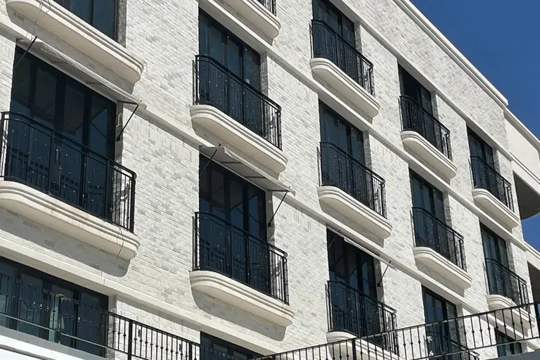 Contemporary hotel complex with white and dark contrasting facades, modern design, and desert landscaping at entrance