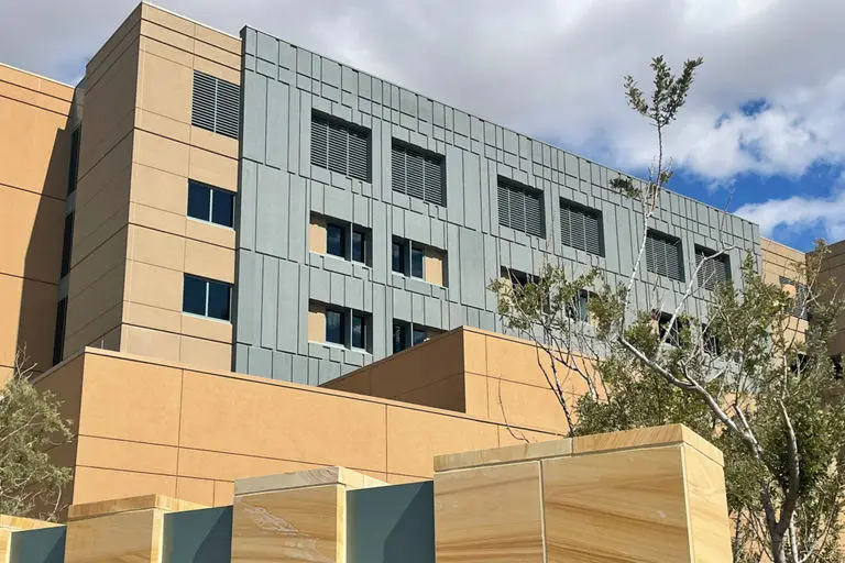 Close-up of the Mayo Clinic building showing modern architectural design with a mix of beige and gray panels and trees.